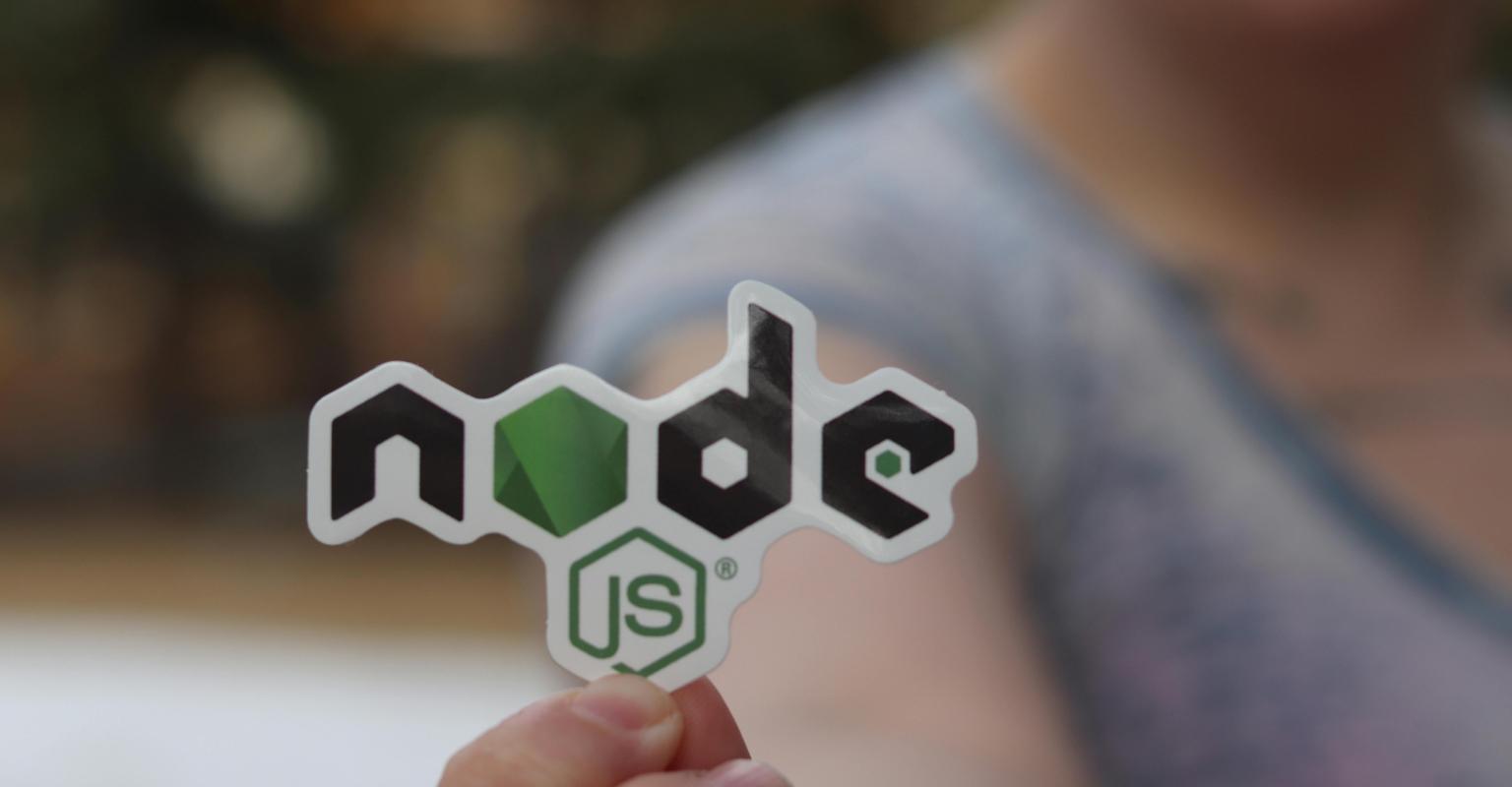hand holding up a sticker that reads 'node js