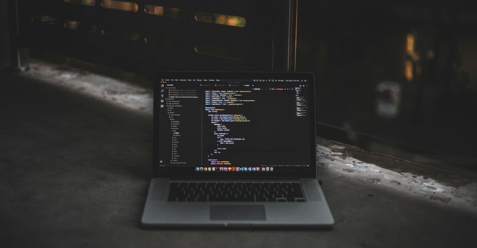 macbook standing on concrete with code on screen